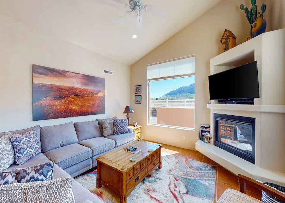 Una sala de estar con asientos, una mesa de centro y un televisor sobre la chimenea.
