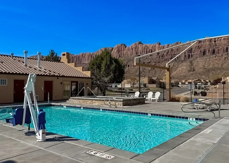 Zona común: Una piscina al aire libre junto a un edificio bajo y colinas rocosas.