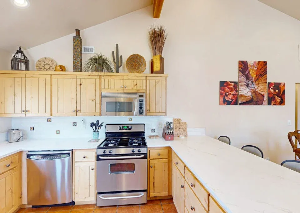 Una cocina luminosa con gabinetes de madera, electrodomésticos de acero inoxidable y una barra larga.