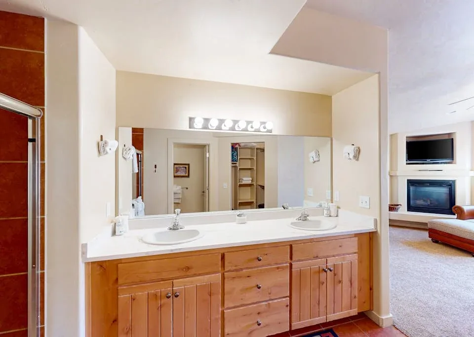 Un tocador de baño con un espejo amplio y gabinetes de madera.