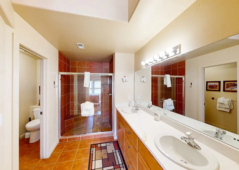 Un baño con un lavabo largo y una zona de ducha con azulejos.