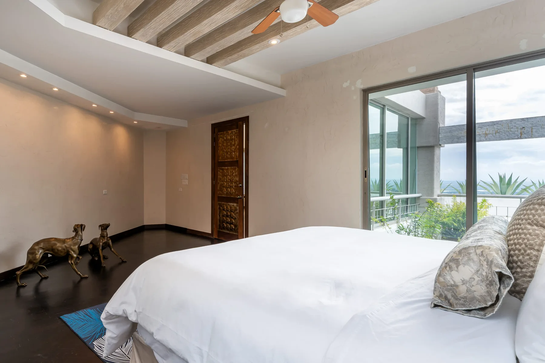 A bedroom with a large bed beside sliding glass doors opening onto a patio.