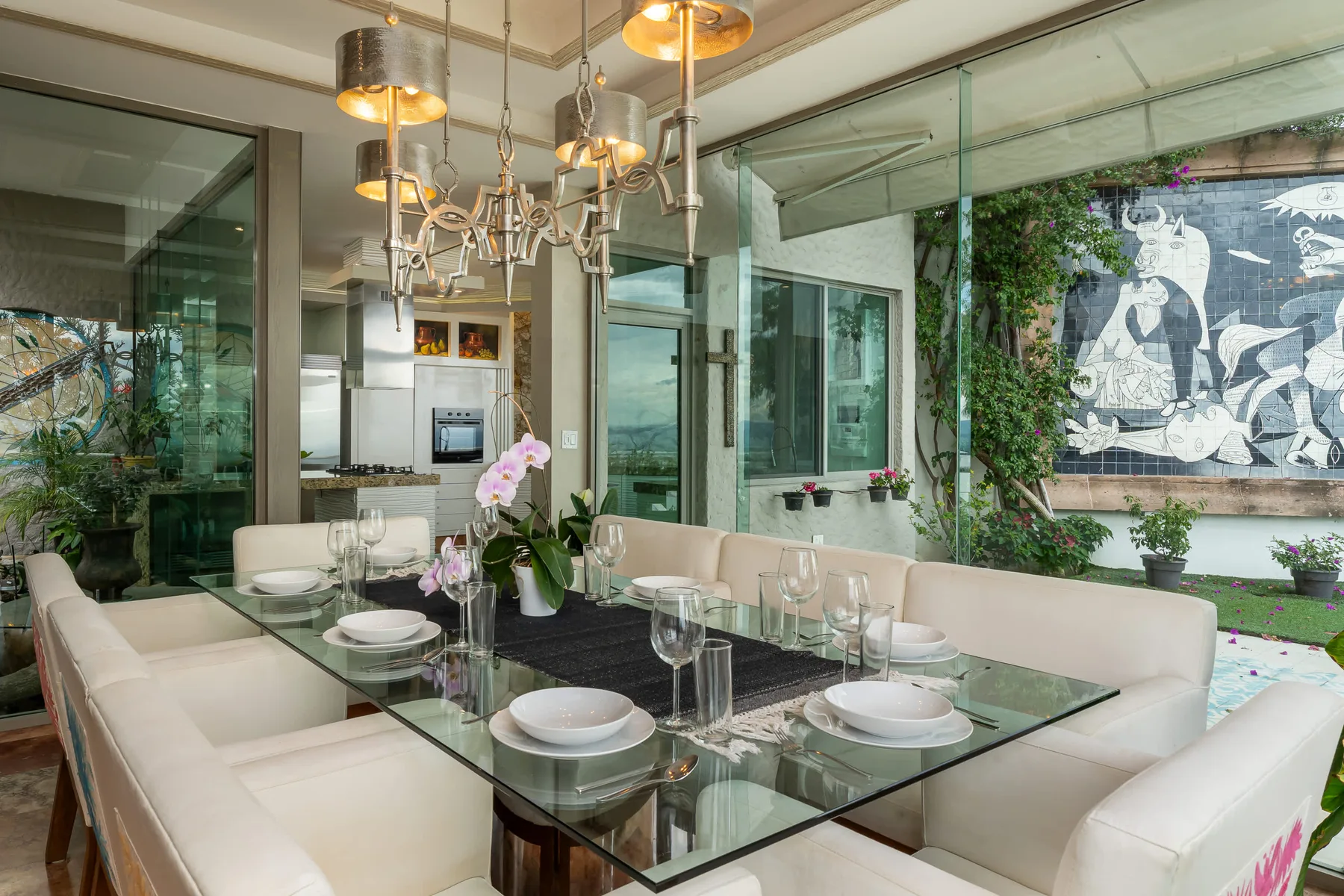 A dining area with a glass table and cream-colored seating beside large windows.