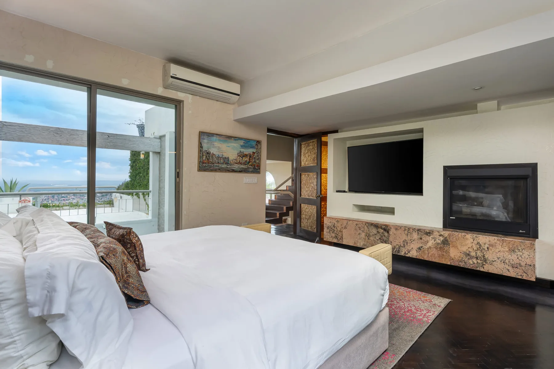 A bedroom with a large bed beside a sliding glass door overlooking the sea.