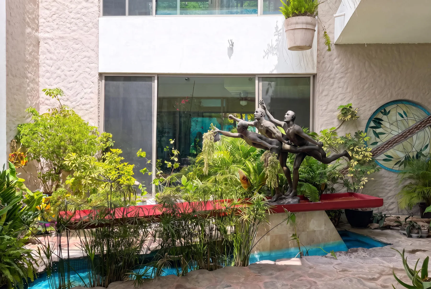 A courtyard garden with a sculpture beside a narrow pool.
