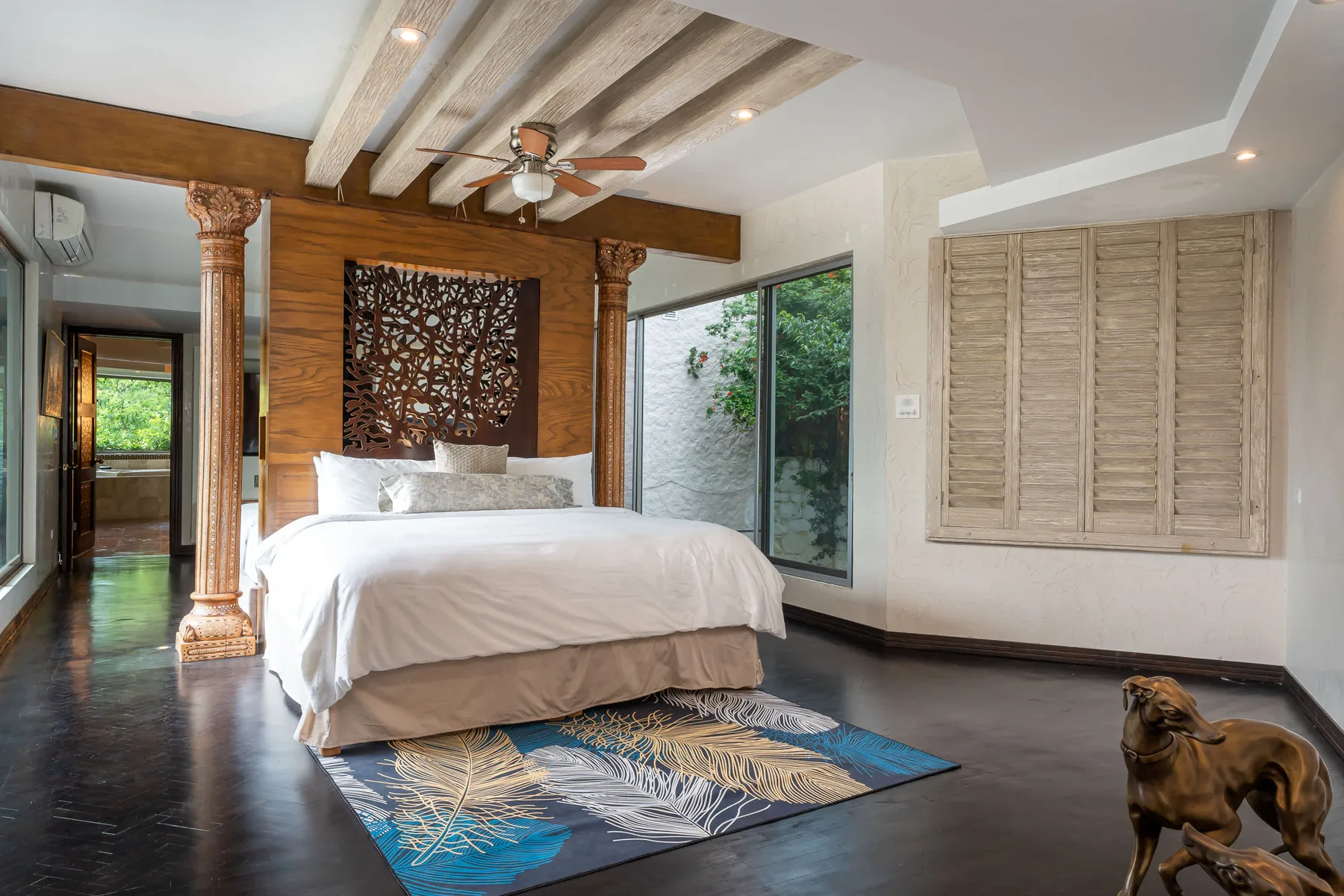 A bedroom with a white bed and a patterned rug on the floor.