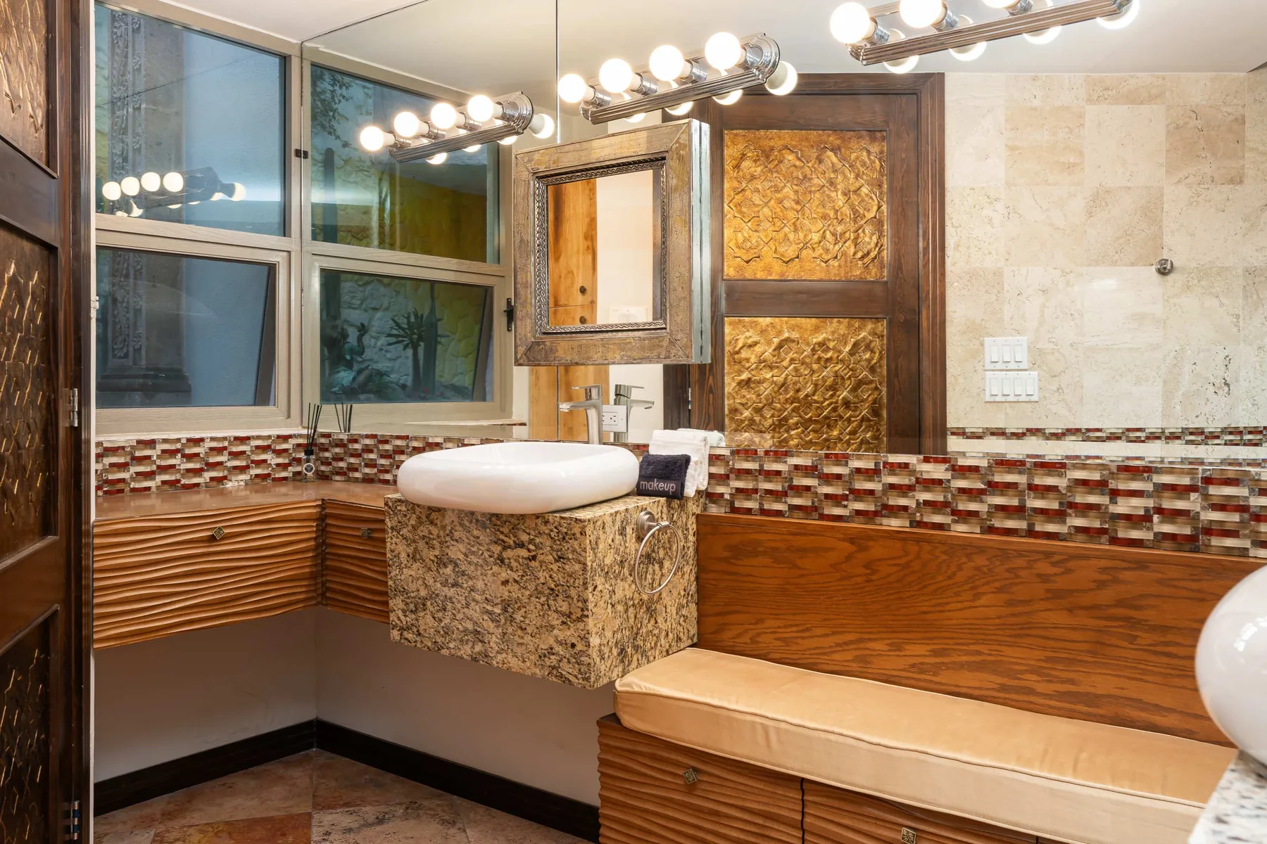 A bathroom vanity with a basin and large mirrors beside a tiled wall.