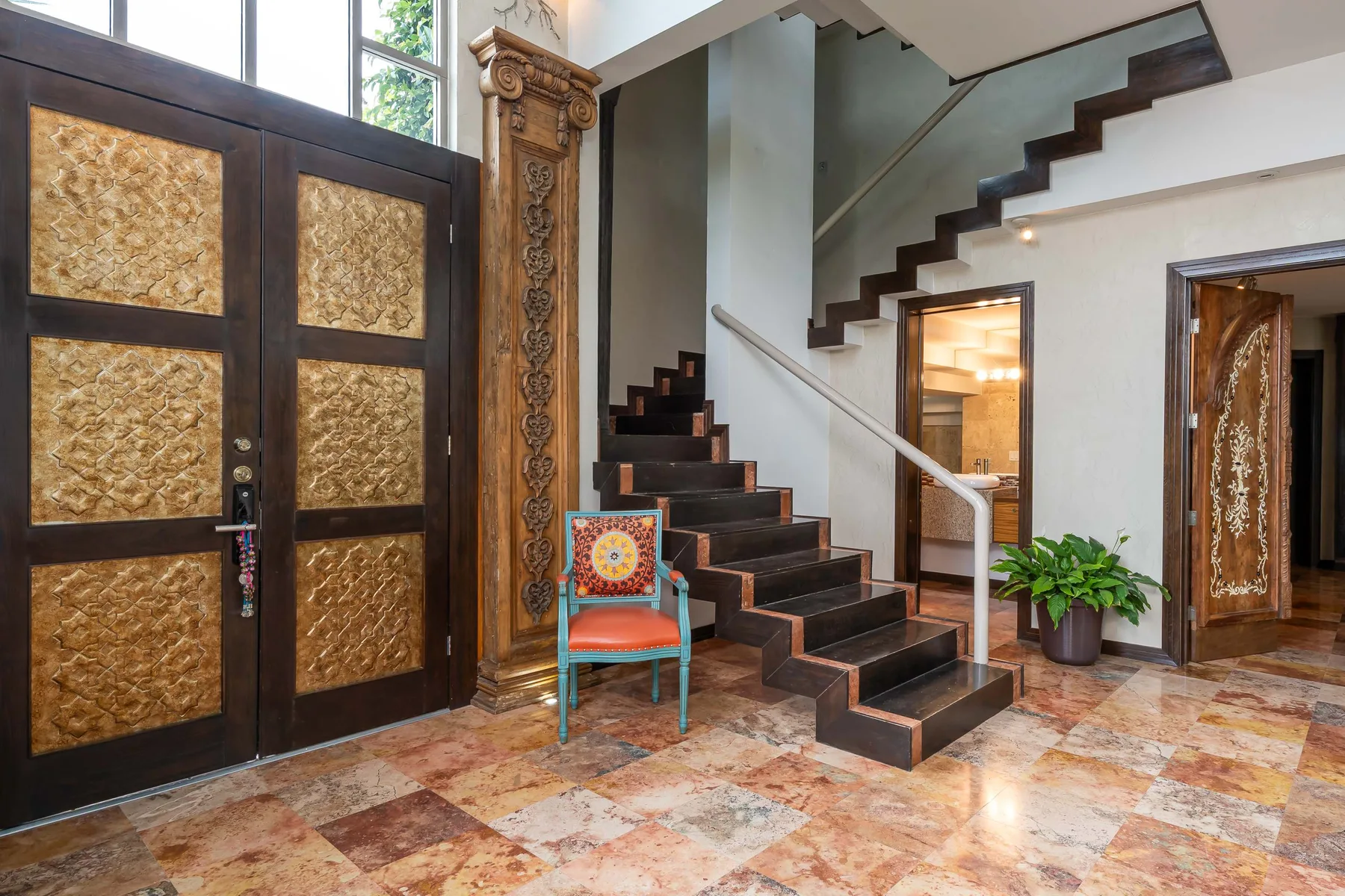 An interior entryway with a staircase and ornate double doors.