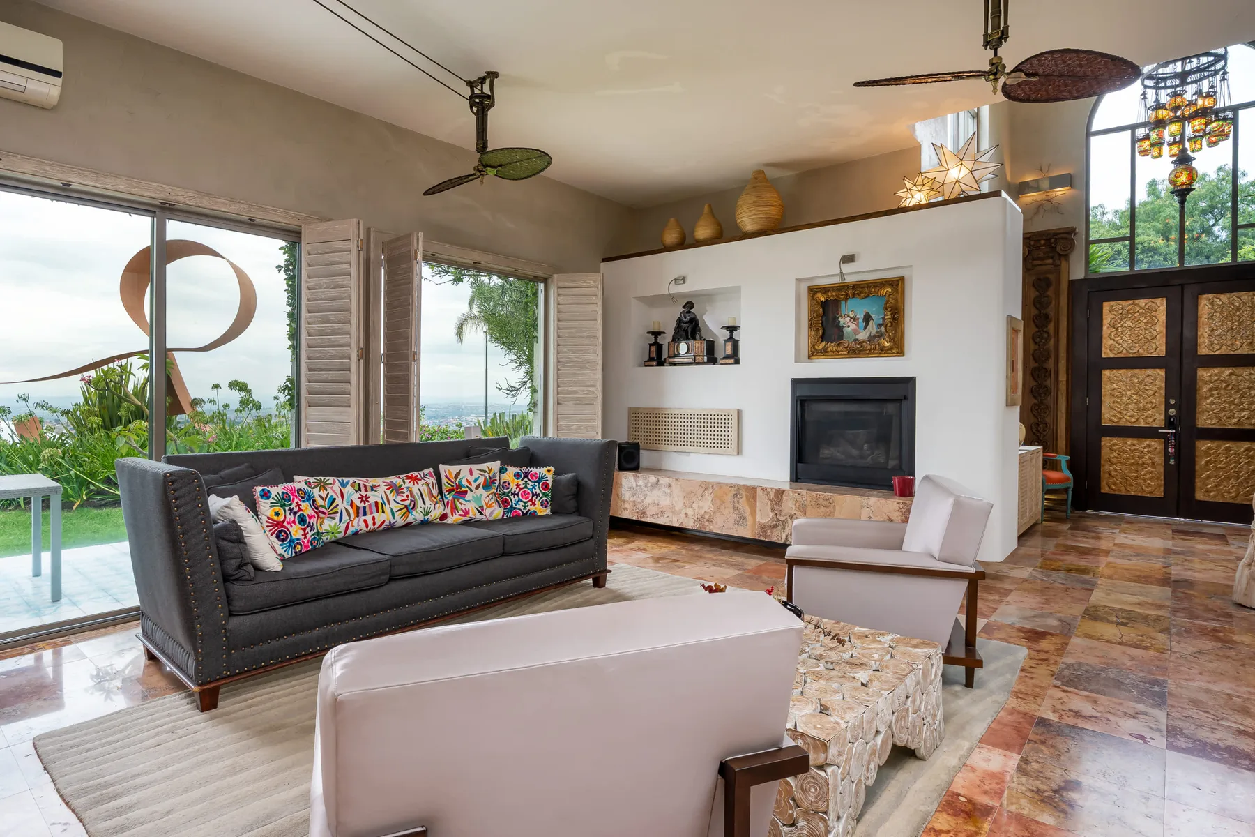A living room with a dark sofa, pale seating, and a fireplace.