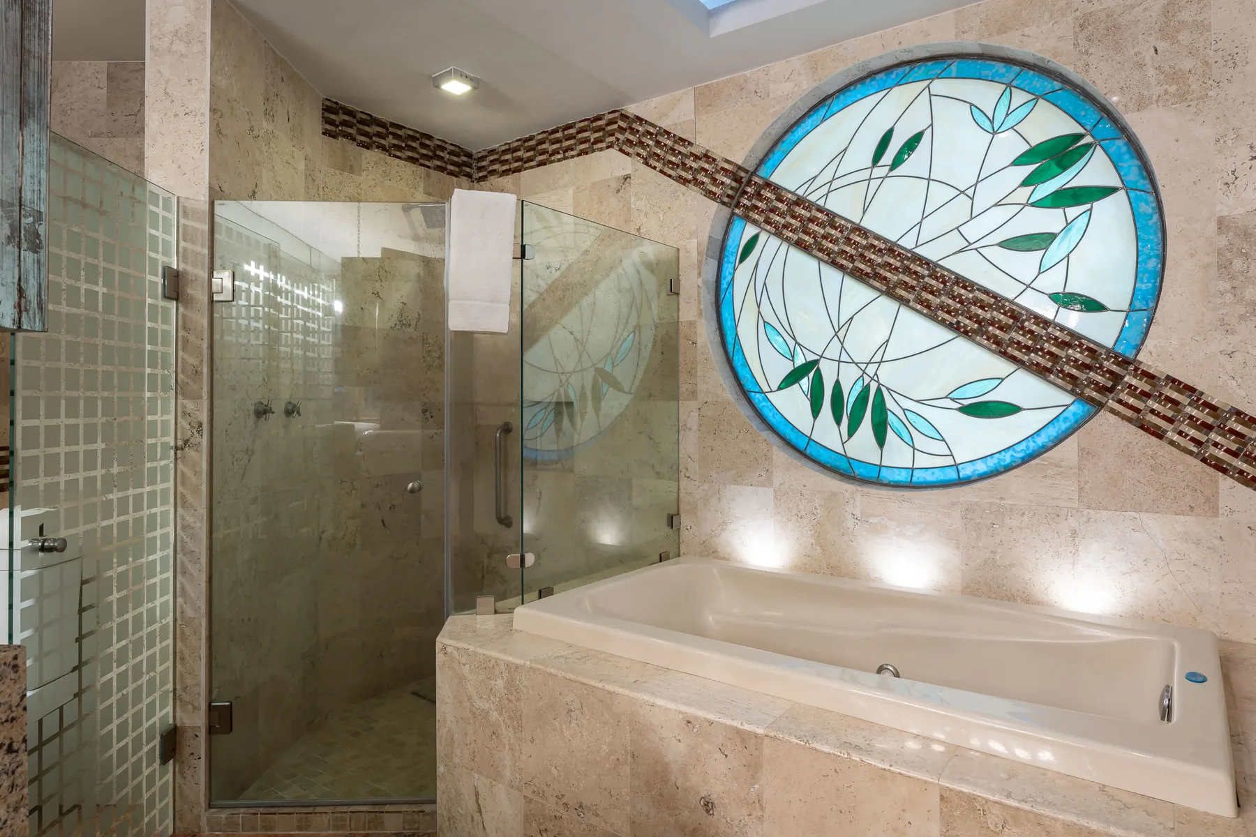 A bathroom with a glass shower enclosure, bathtub, and large circular stained-glass window.
