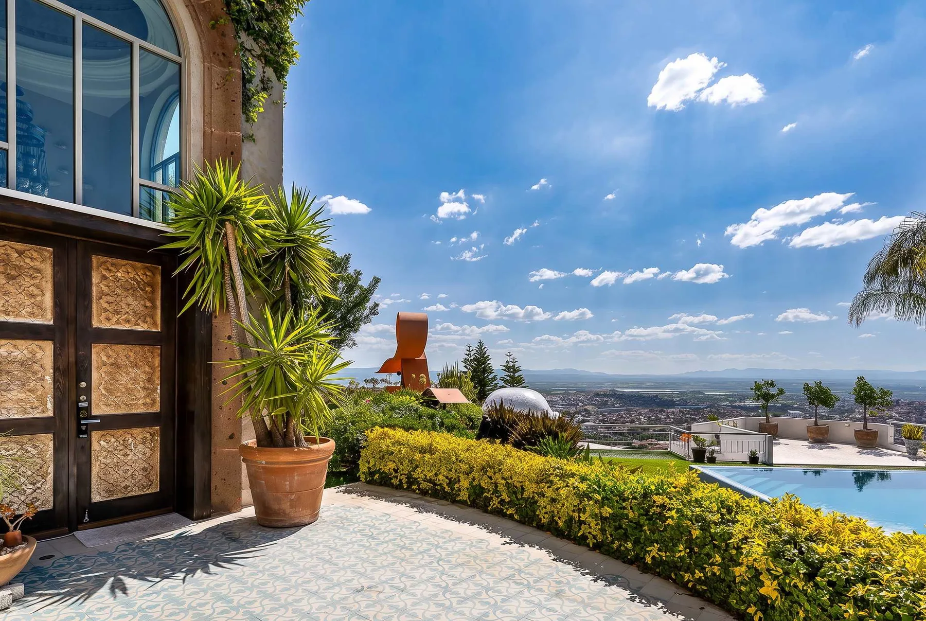 Shared amenity: A sunny terrace overlooks a swimming pool, gardens, and a distant landscape.