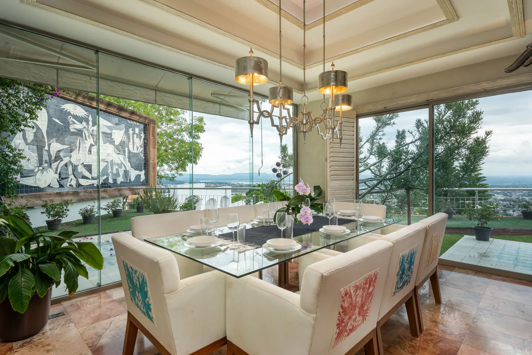 A dining room with a glass table and upholstered seating beside large windows.