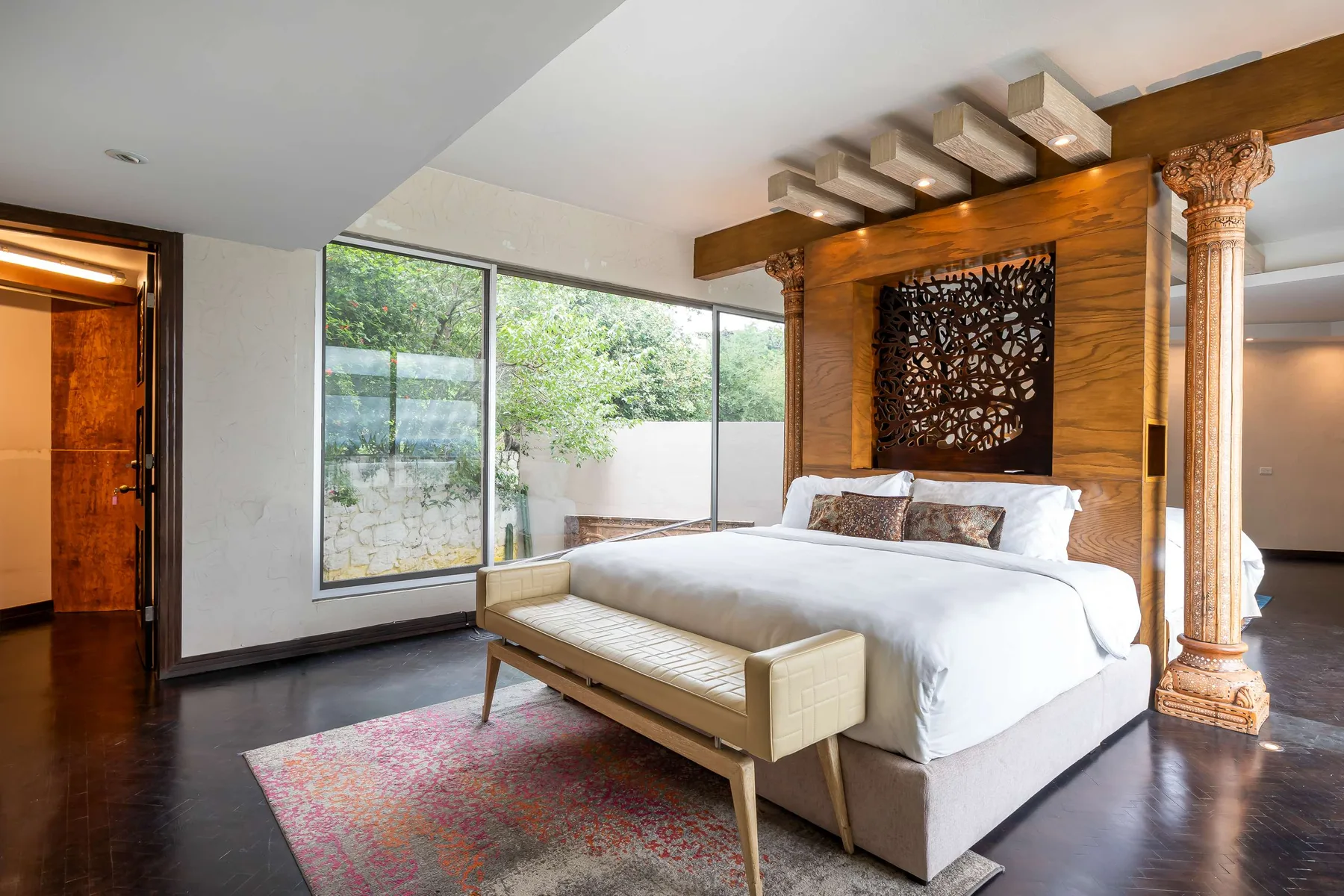 A bedroom with a large bed beside floor-to-ceiling windows.