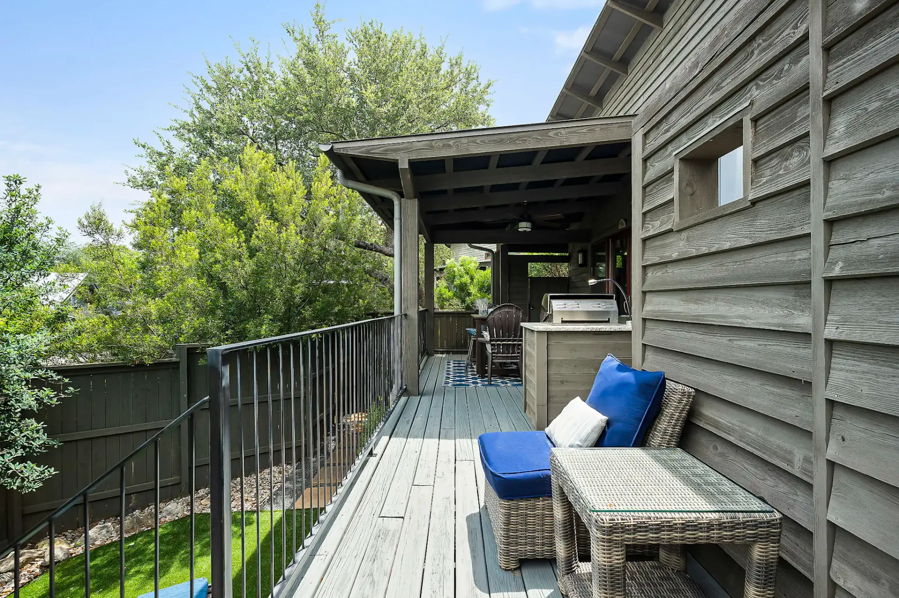 Una terraza exterior cubierta con asientos y una encimera junto a una casa de madera.