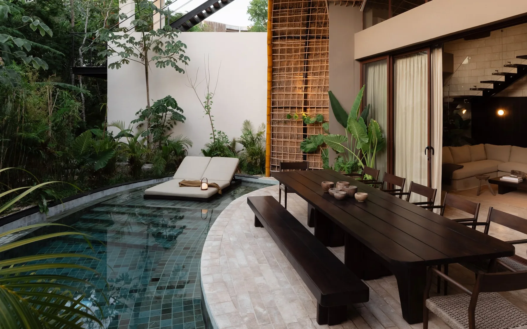 A courtyard dining area beside a small pool, with lush plants around the patio.