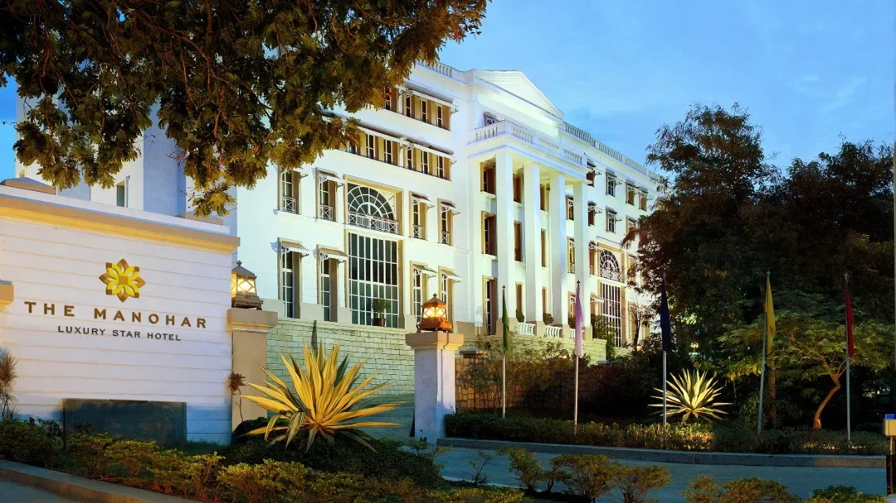 Espacio representativo del hotel: Un gran edificio hotelero blanco se alza detrás de una entrada ajardinada.