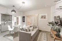 A bright living room with a sofa, dining table, and kitchen area.