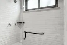 A tiled shower area with a wall-mounted grab bar and window.