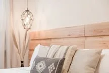 A bedroom with a bed, patterned pillows, and a hanging light.