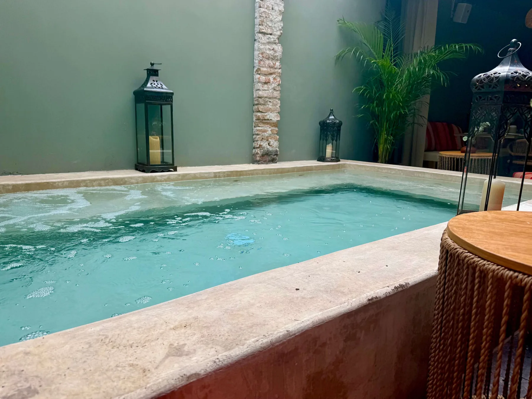 Shared amenity: An indoor pool with lanterns and a potted palm nearby.