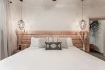 A bedroom with a bed, wooden headboard, and pendant lights.