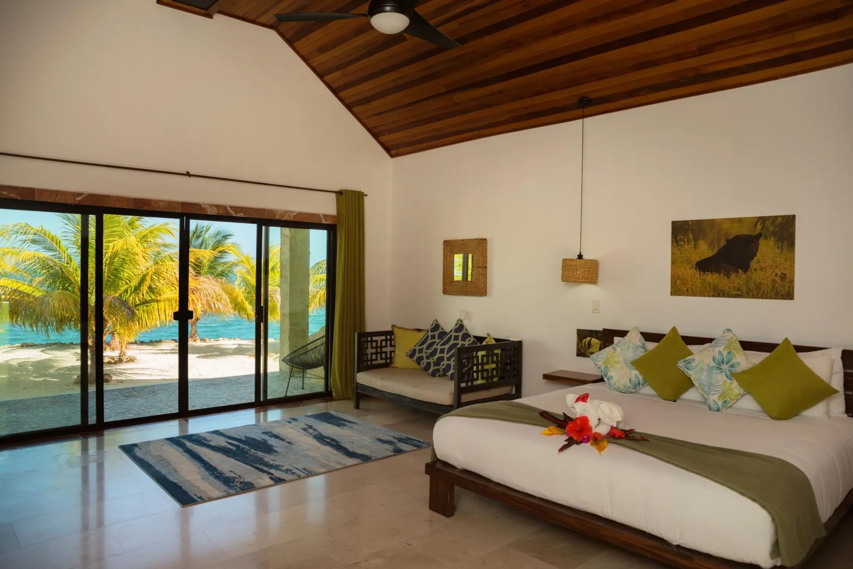 A bedroom with a large bed, seating, and sliding glass doors opening to a beach view.
