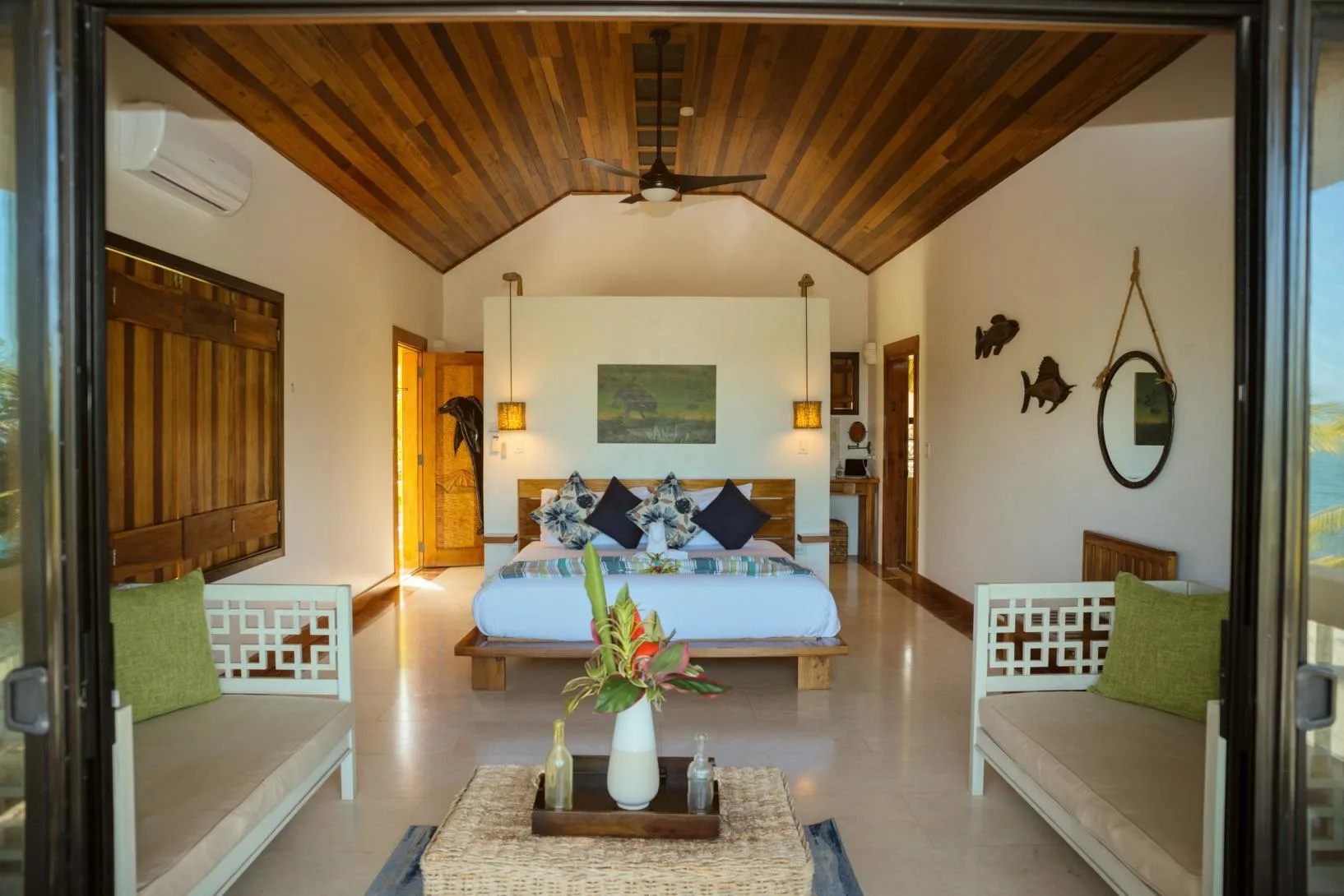 A bedroom with a large bed beneath a vaulted wooden ceiling.