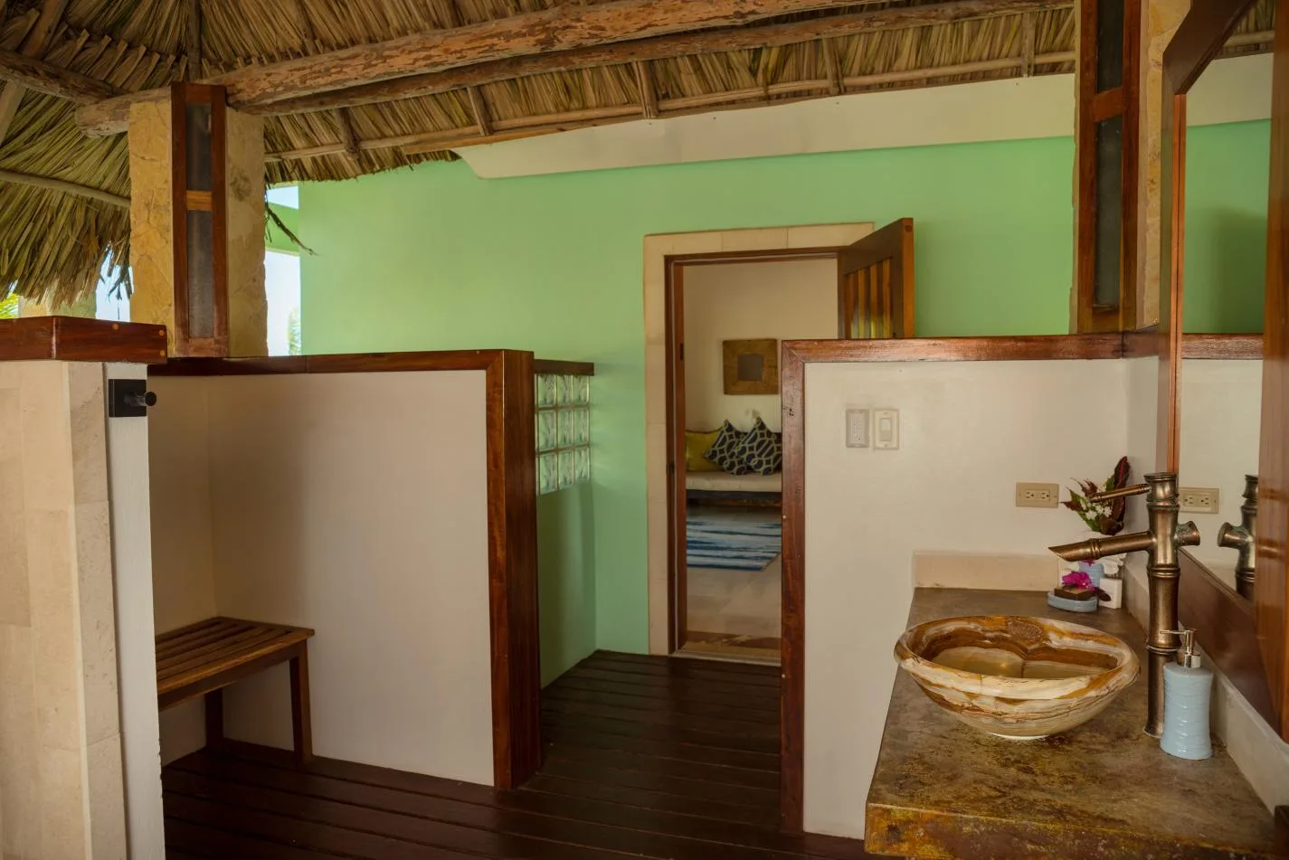A bathroom vanity with a bowl sink stands beside a doorway to a bedroom.