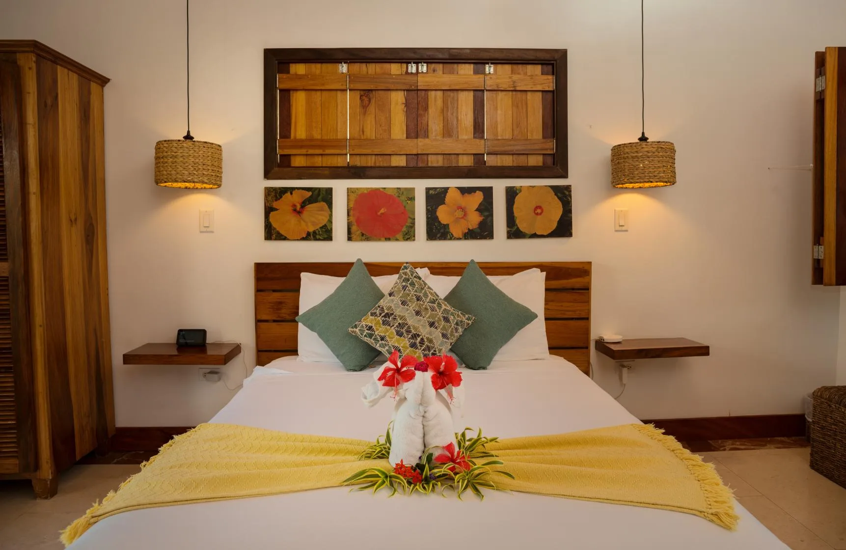 A bedroom with a neatly made bed, decorative pillows, and floral artwork above the headboard.
