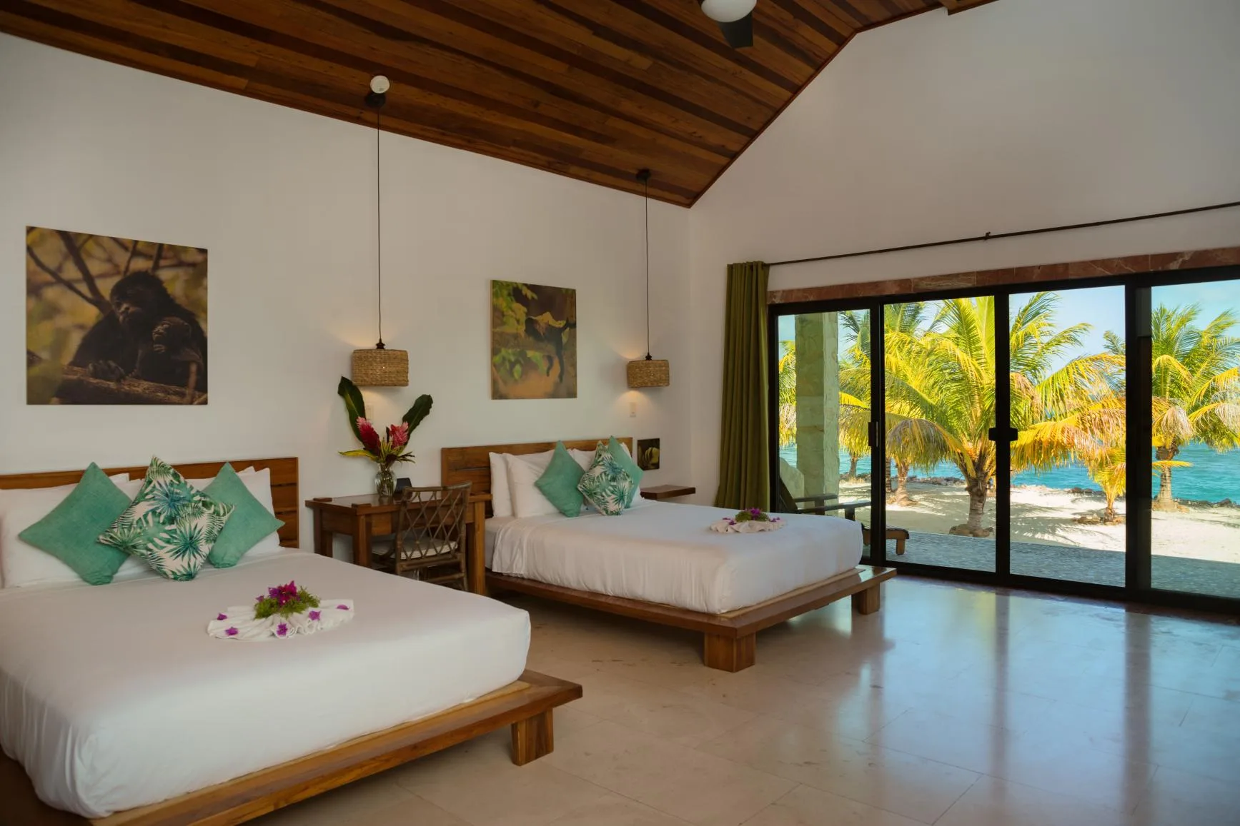 A bedroom with two beds and glass doors opening onto a palm-lined view.