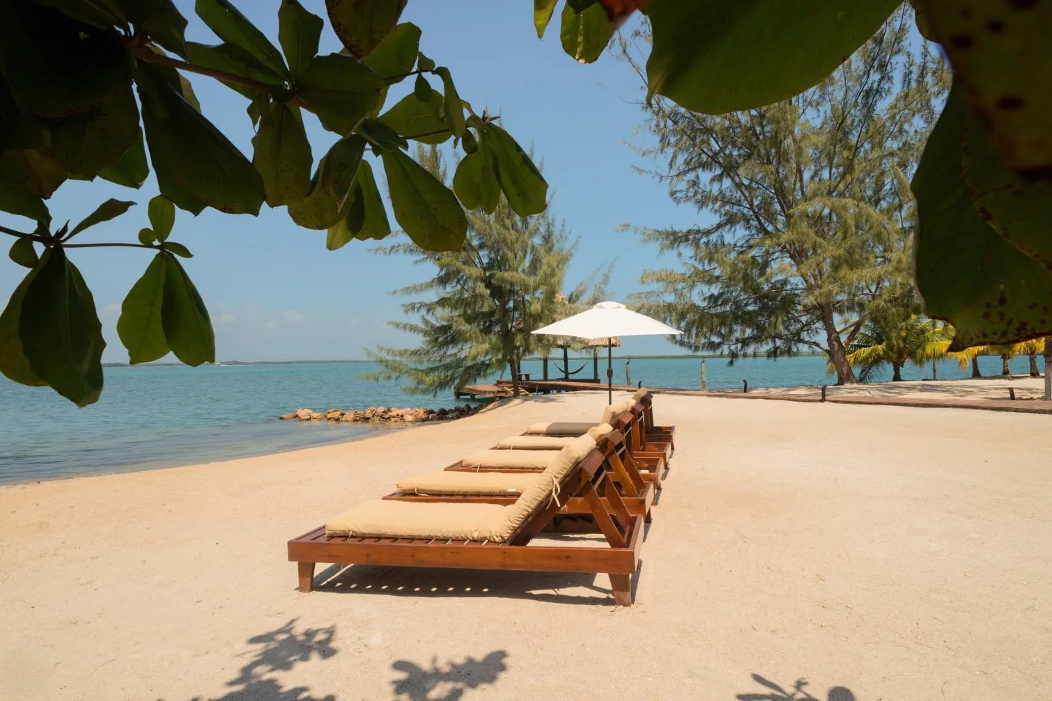 A sandy beach with wooden lounge chairs facing the calm sea.