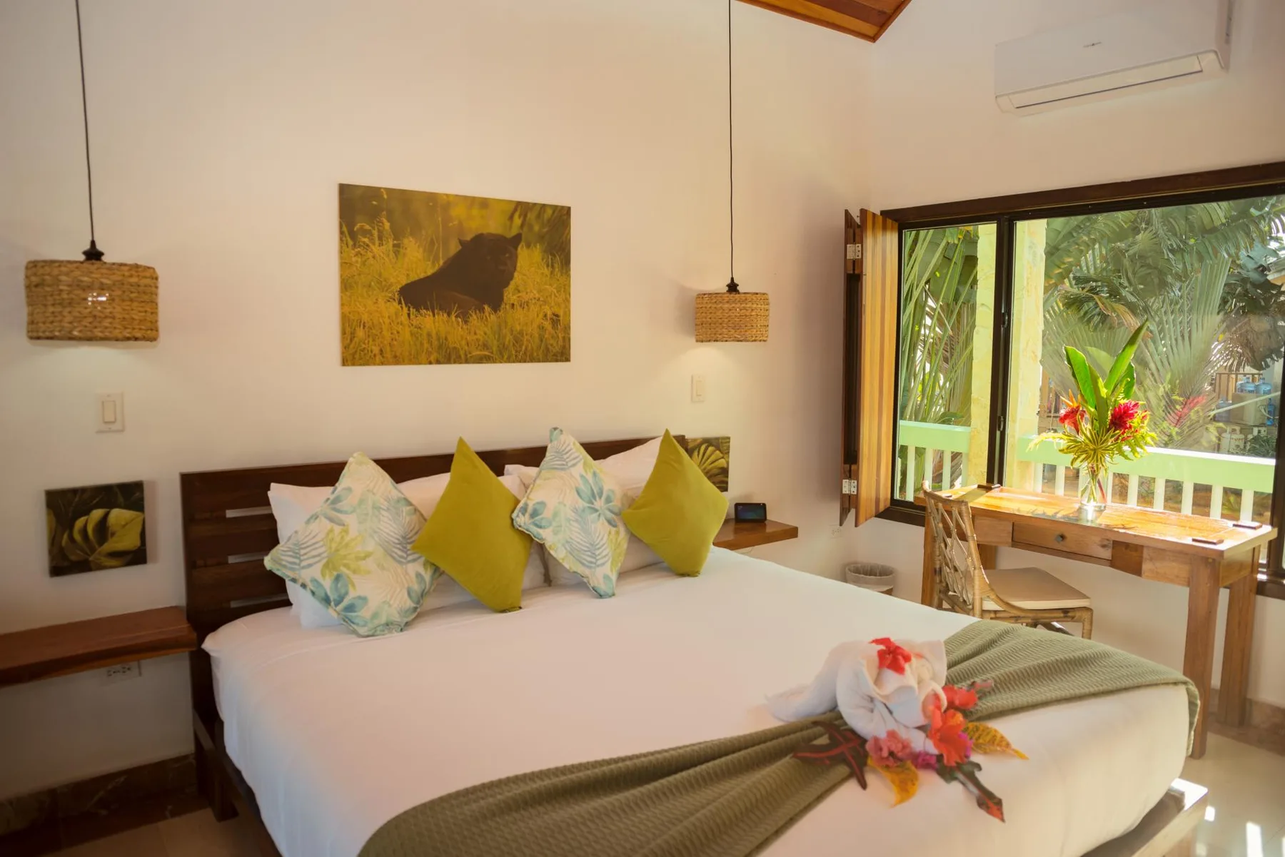 A bedroom with a bed and a large window overlooking lush greenery.