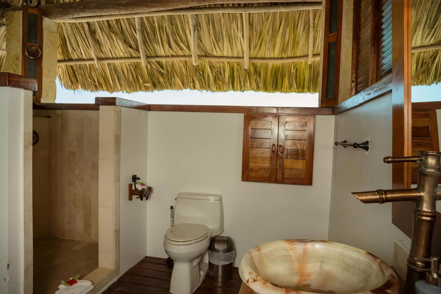 A bathroom with a toilet, shower area, and a bowl-shaped sink.