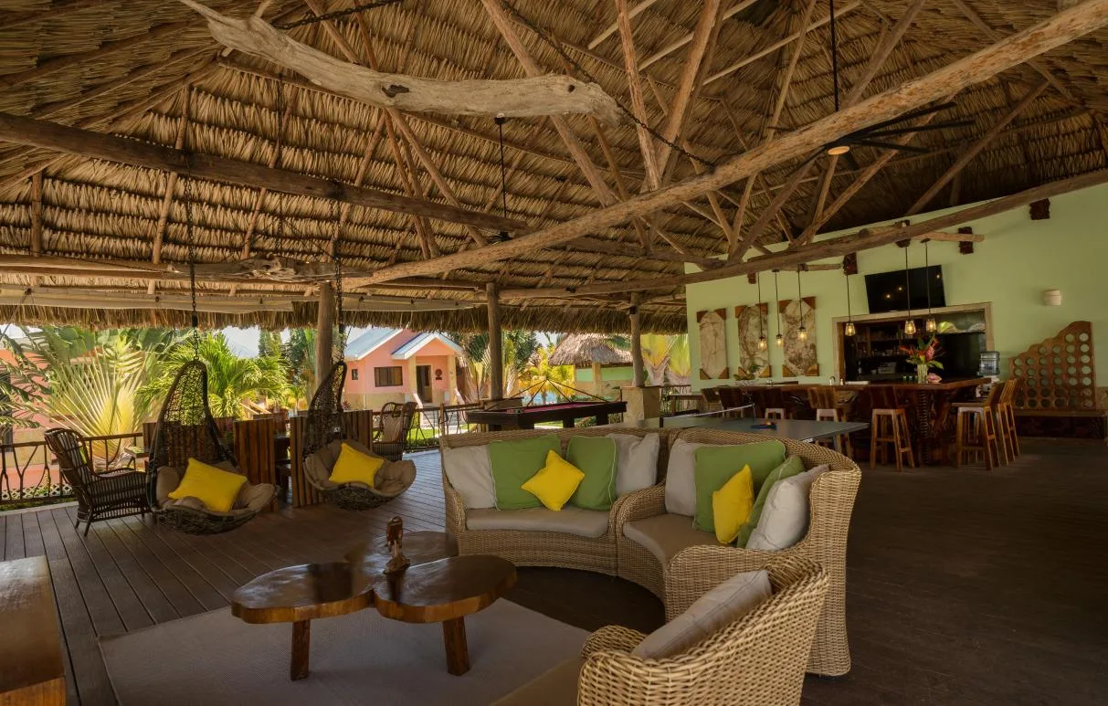 An open-air lounge with wicker seating beneath a thatched roof.