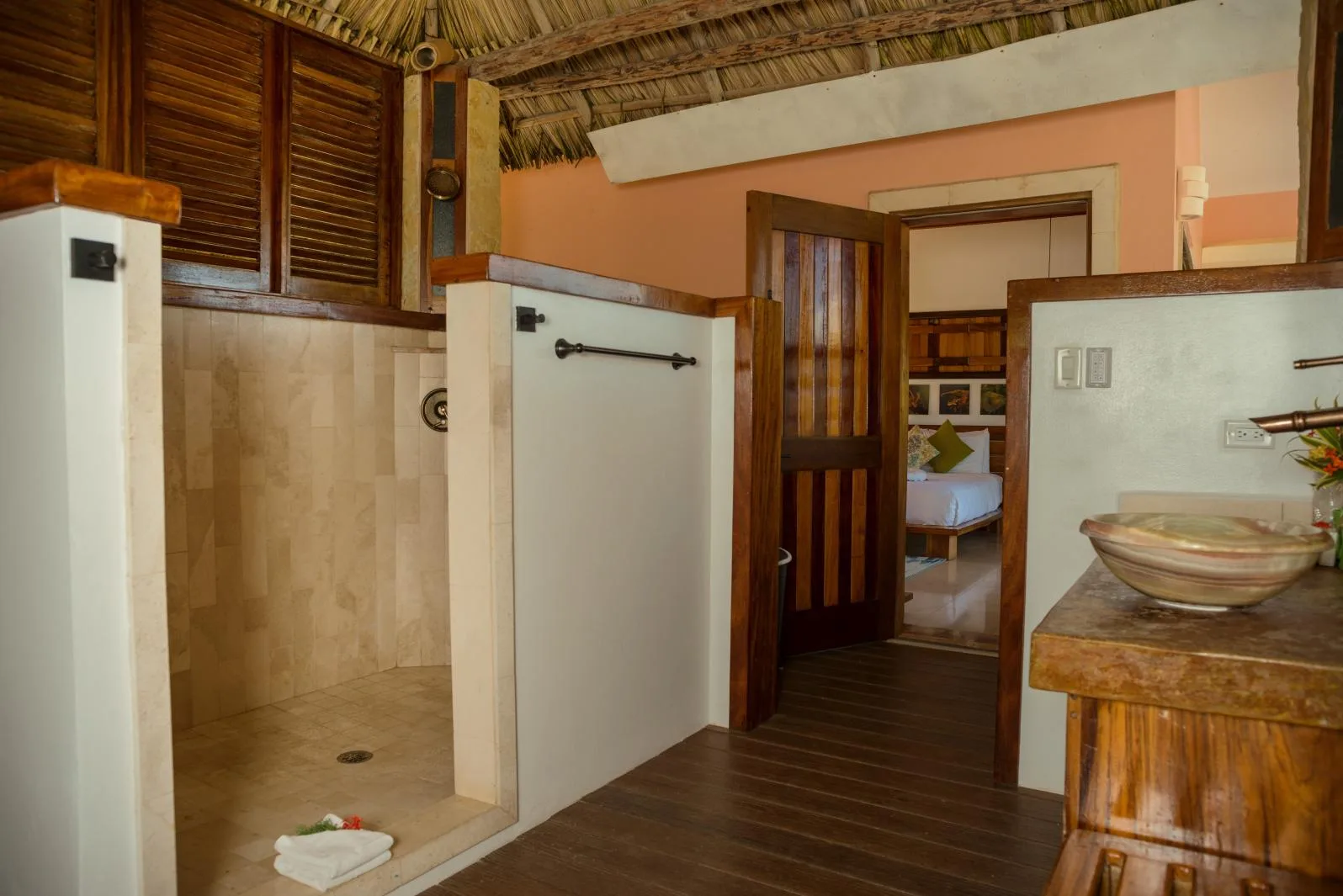 A bathroom with a walk-in shower and a wooden vanity beside an open doorway.