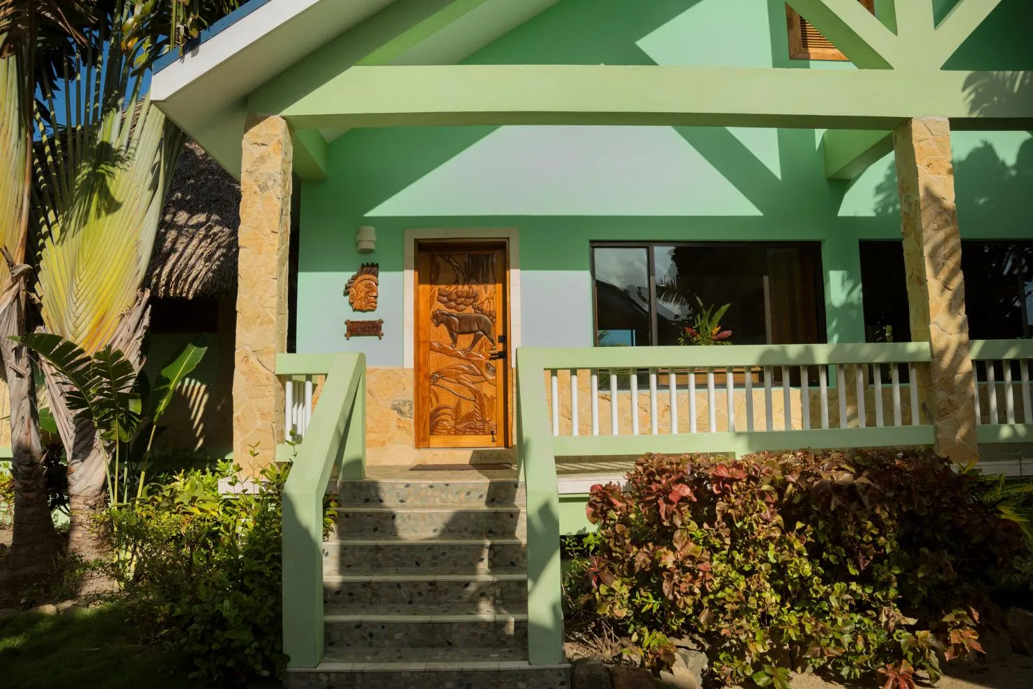 A green house entrance with front steps and a wooden door.