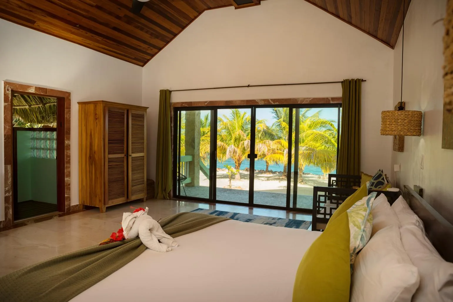 A bedroom with a large sliding glass door opening onto a palm-lined view.