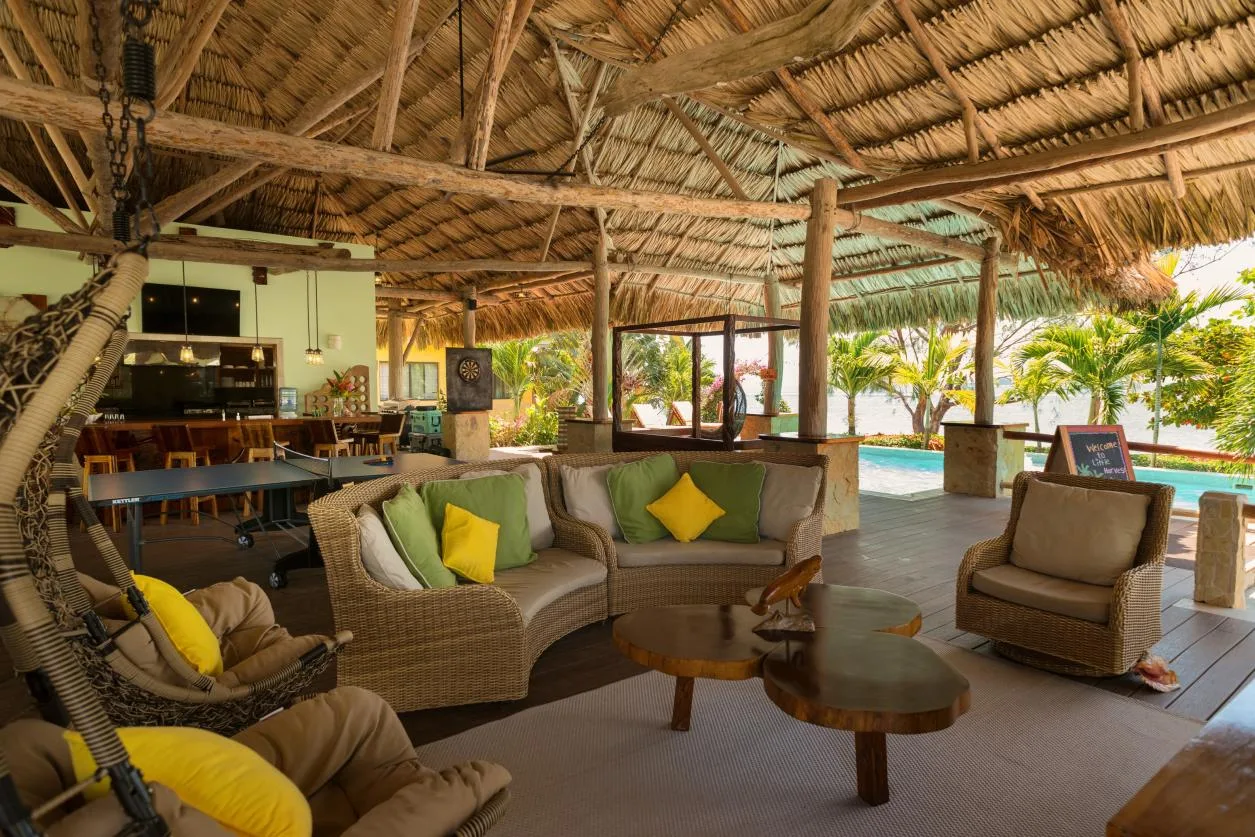 A covered outdoor lounge with wicker seating and a poolside view.