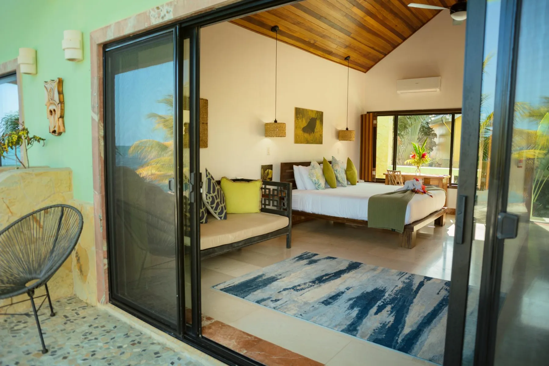 A bedroom with a bed, seating, and a blue patterned rug.