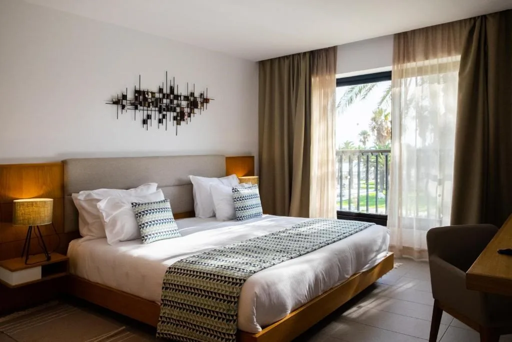 Espacio representativo del hotel: Dormitorio de hotel con una cama bien hecha junto a una ventana.