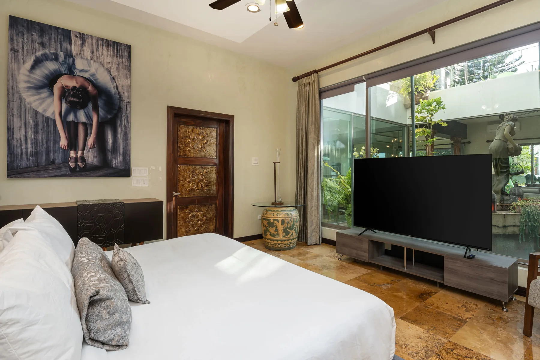Un dormitorio con una cama grande, un televisor y puertas de vidrio con vista a un patio.