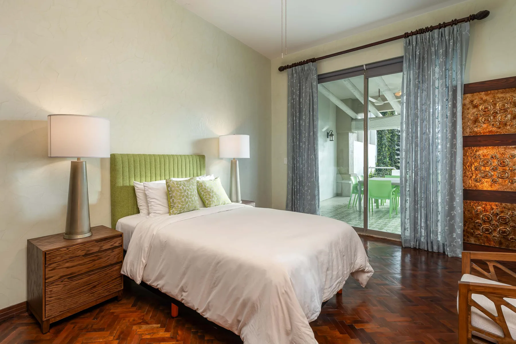 Dormitorio con una cama junto a una puerta de cristal que da a un patio.