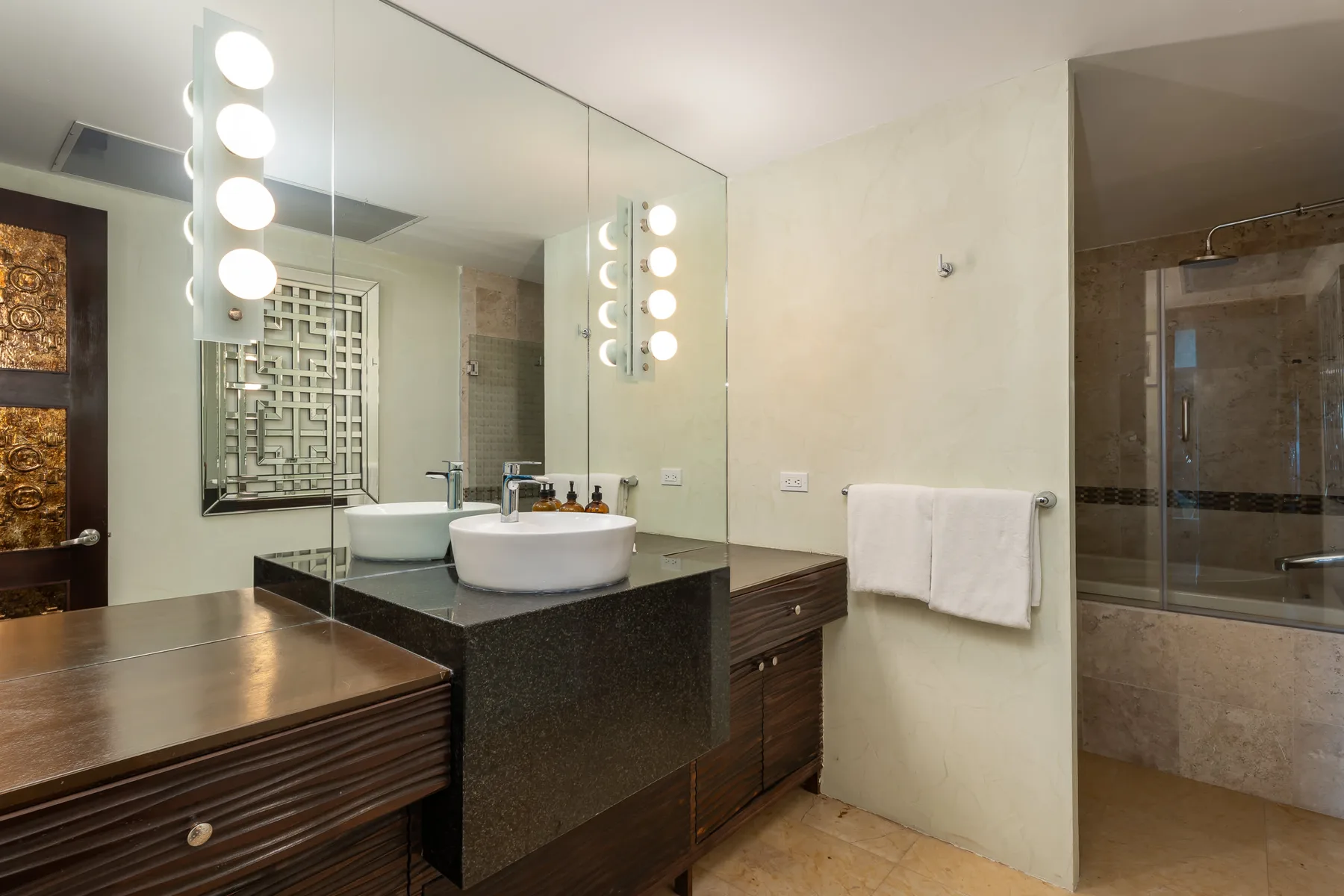 Un tocador de baño con lavabos sobrepuestos y un gran espejo de pared.