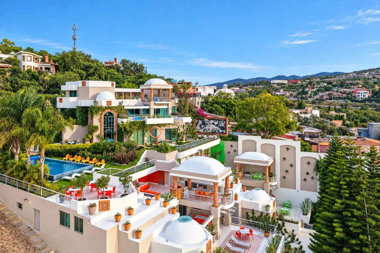 Zona común: Una propiedad en una ladera con edificios blancos, terrazas ajardinadas y una piscina.