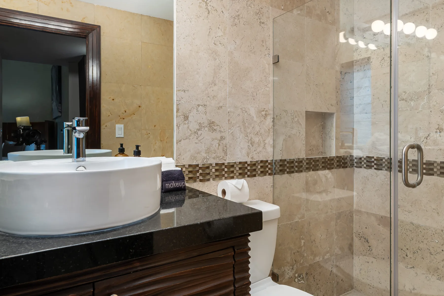 Un baño con un lavabo blanco y una ducha con mampara de vidrio.