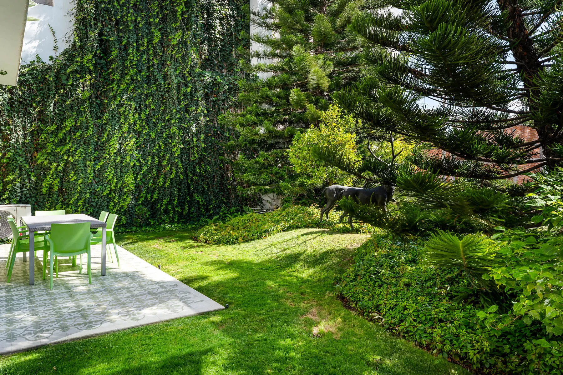 Un patio de jardín con asientos al aire libre junto a un césped y árboles.