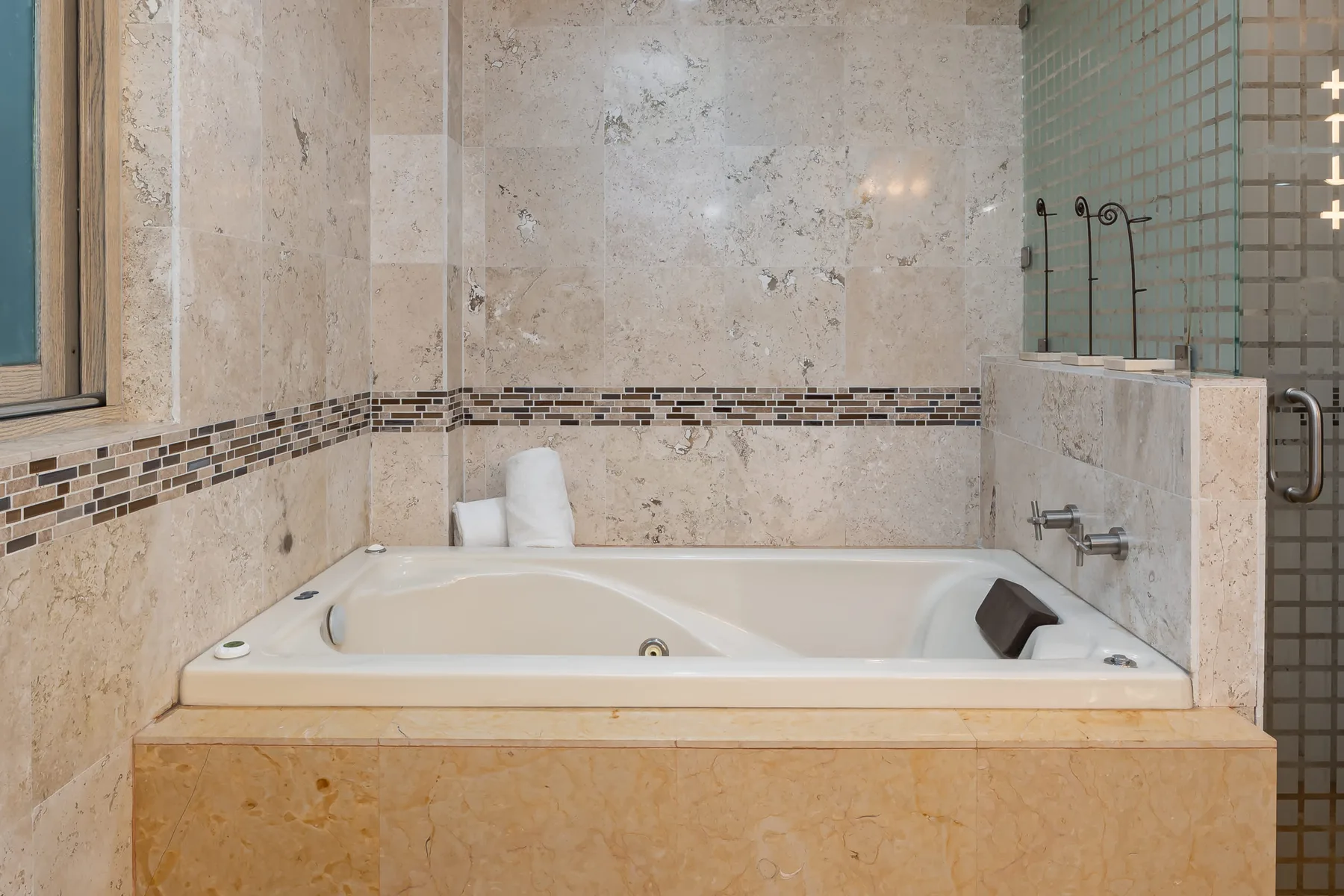 Una bañera empotrada está en un baño con azulejos.