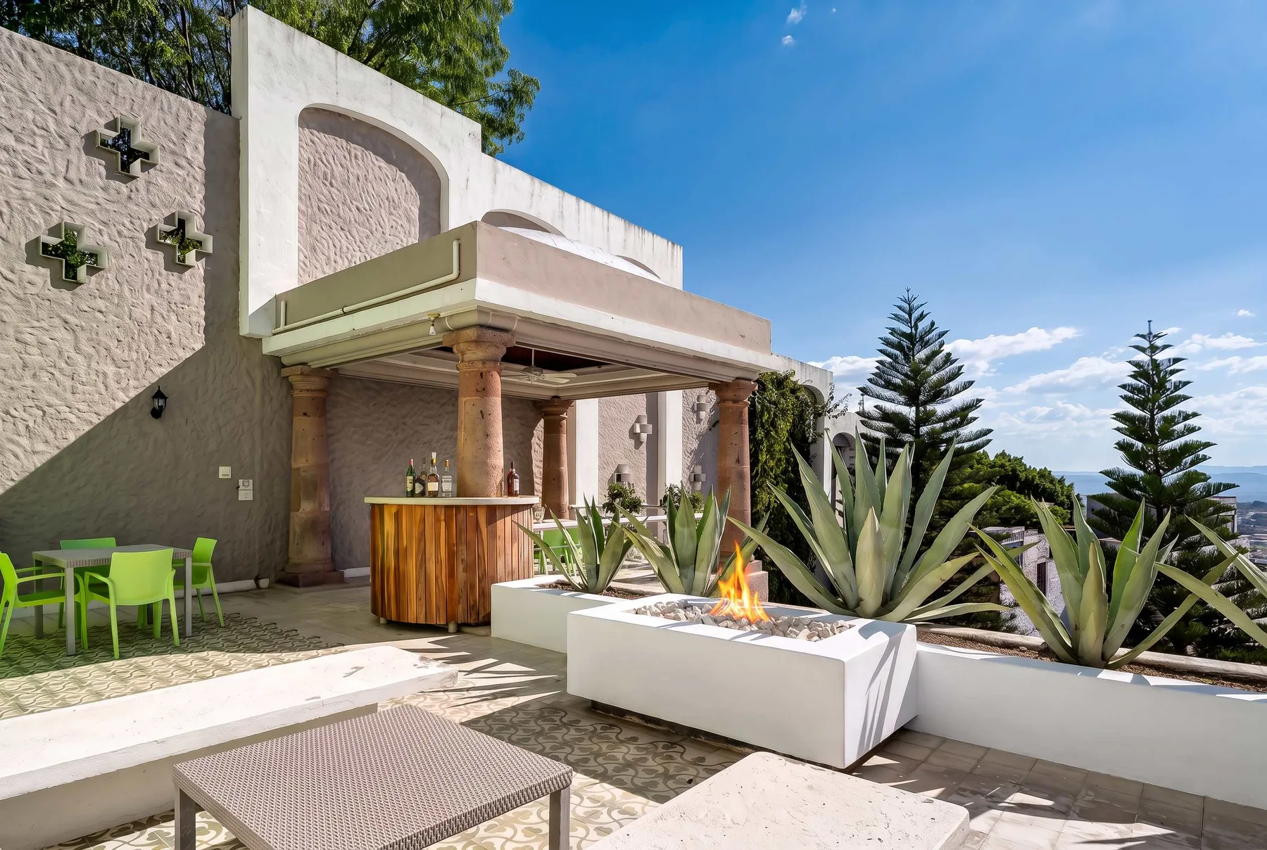 Un patio al aire libre con una barra cubierta, asientos y grandes jardineras.