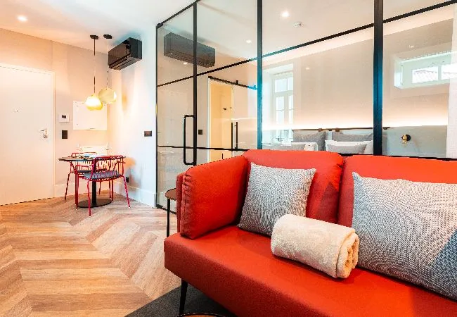 A living area with red seating beside a glass partition and small dining table.