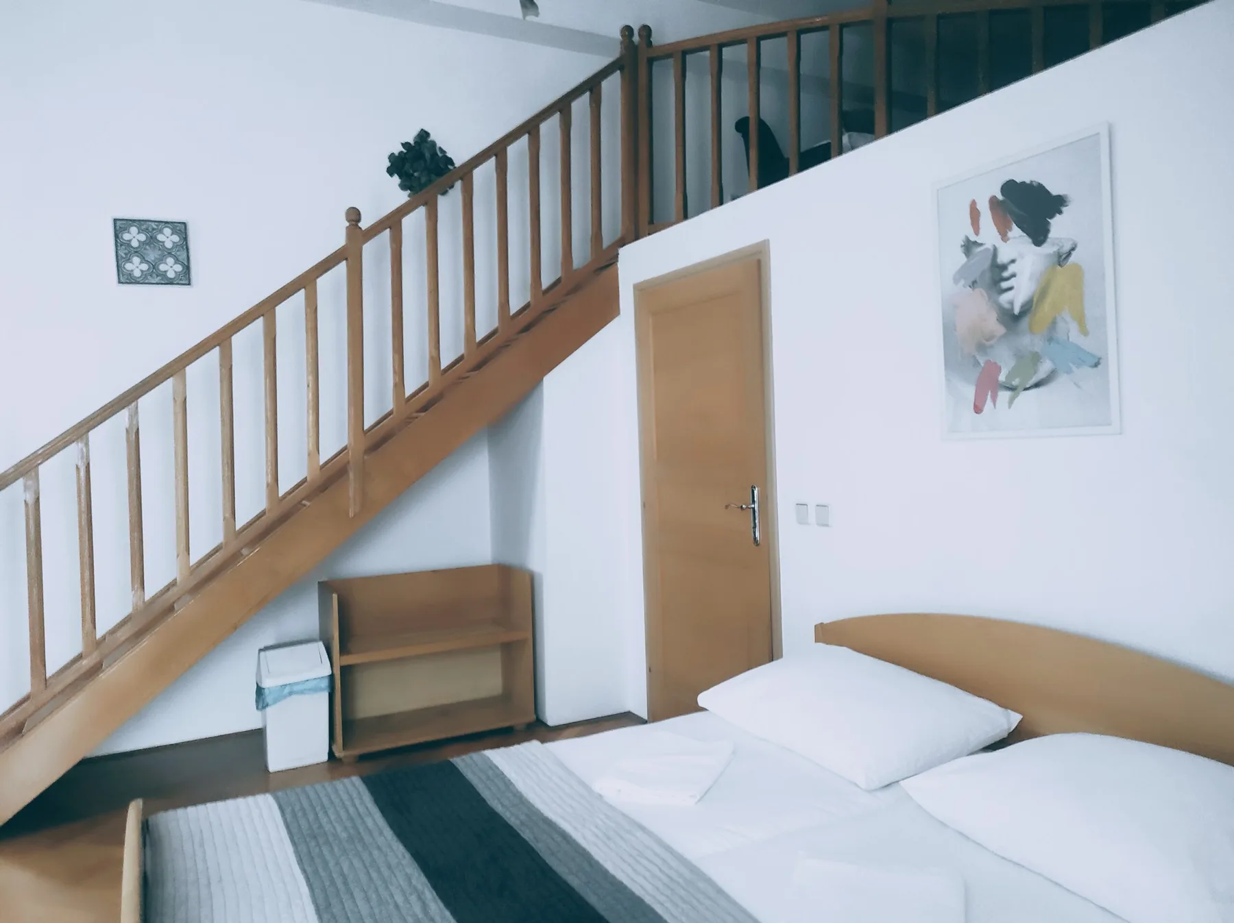 Espacio representativo del hotel: Un dormitorio con una cama bajo una escalera de madera.